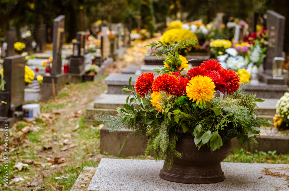 flowers on graves during All Saints Day in the autumnal cemetery