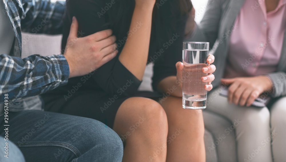 Emotional woman crying with glass of water therapy session
