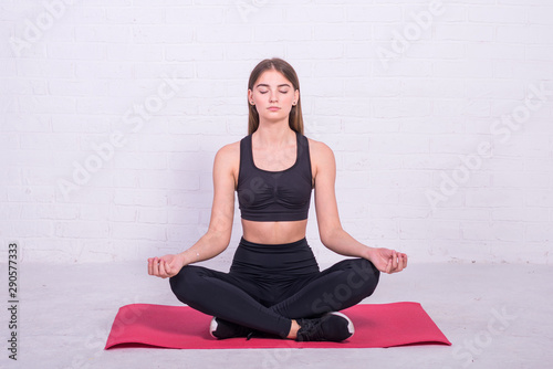 Young slender girl is sitting in lotus position.