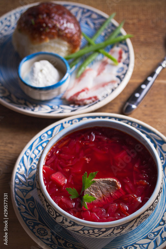 Soup borscht, garlic bun pampushka, sour cream and pork belly. Vertical image