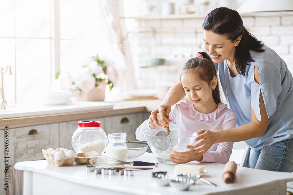 Beautiful mother teaching her daughter how to make dough Beautiful mother teaching her daughter how to make dough