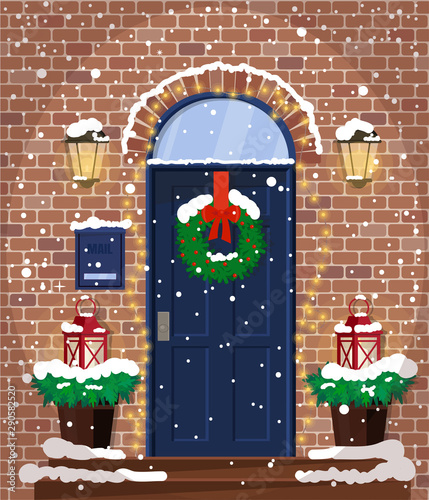 The facade of the house with a door decorated with a Christmas wreath and lanterns.