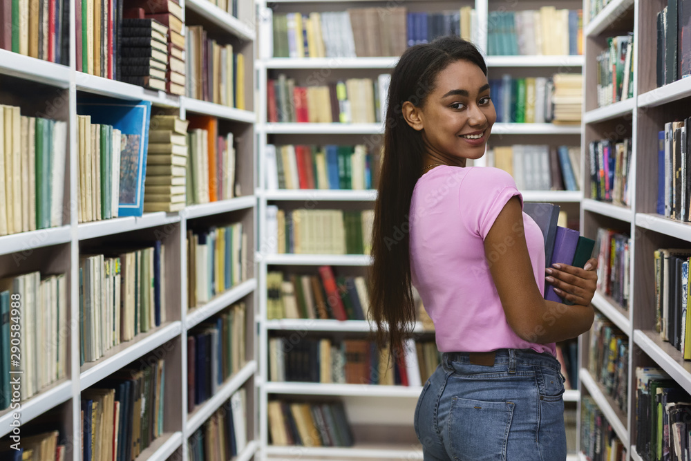 Pretty afro girl posing at camera between bookshelves Pretty afro girl posing at camera between bookshelves