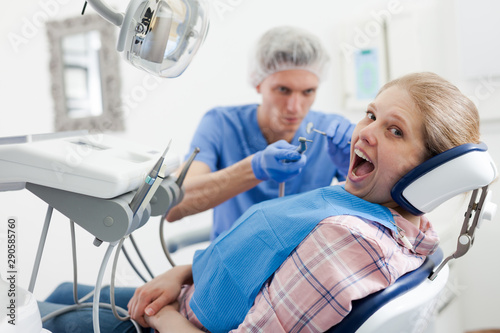 Male dentist treating young female patient in dental office