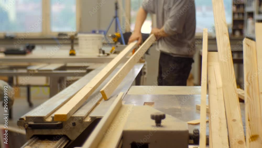 Worker in a carpentry workshop sawing boards on a machine Worker in a carpentry workshop sawing boards on a machine
