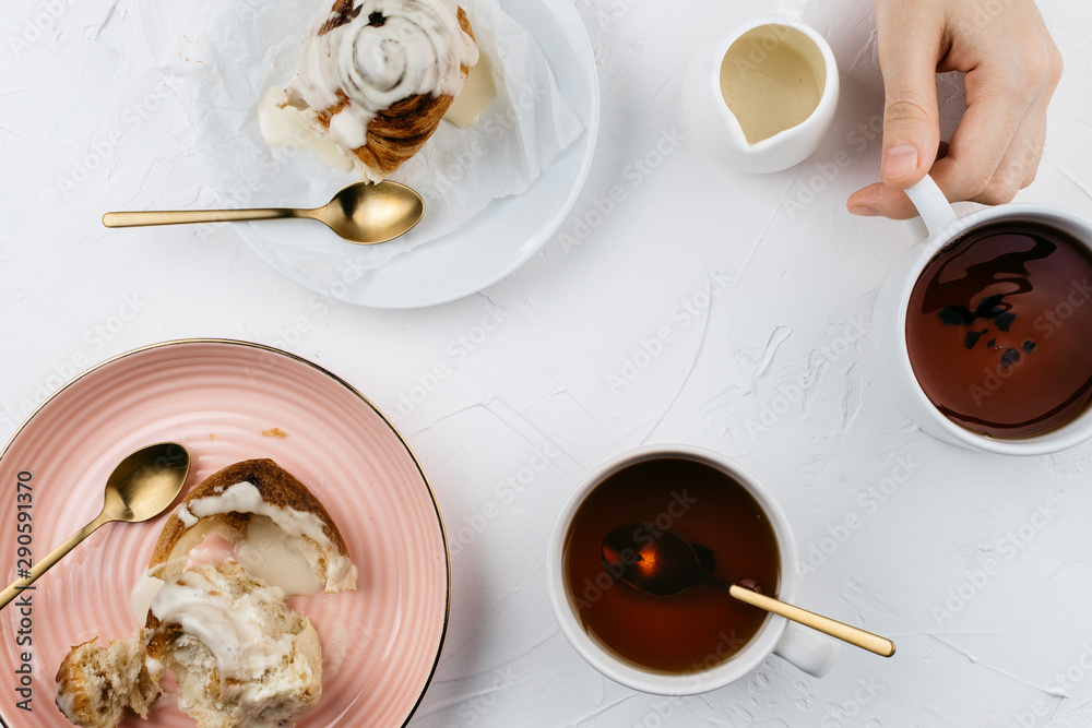 Flatlay of homemade cinnamon rolls with cream and tea on white cement background Flatlay of homemade cinnamon rolls with cream and tea on white cement background