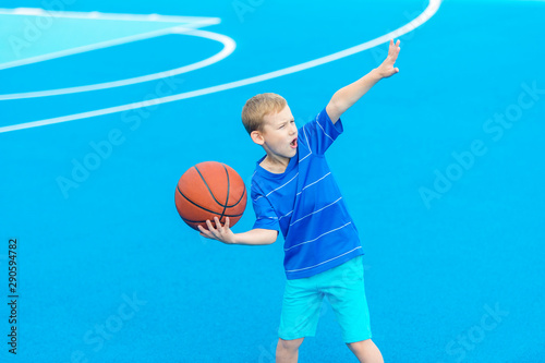 Adorable child playing the basketball in the basket field
