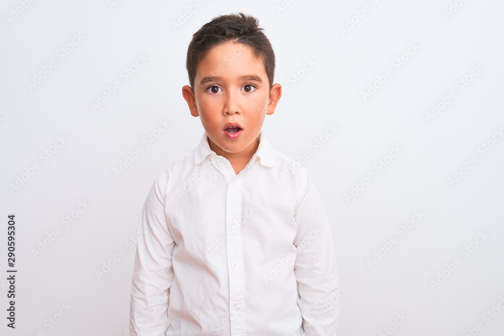 Beautiful kid boy wearing elegant shirt standing over isolated white background afraid and shocked with surprise expression, fear and excited face. Beautiful kid boy wearing elegant shirt standing over isolated white background afraid and shocked with surprise expression, fear and excited face.