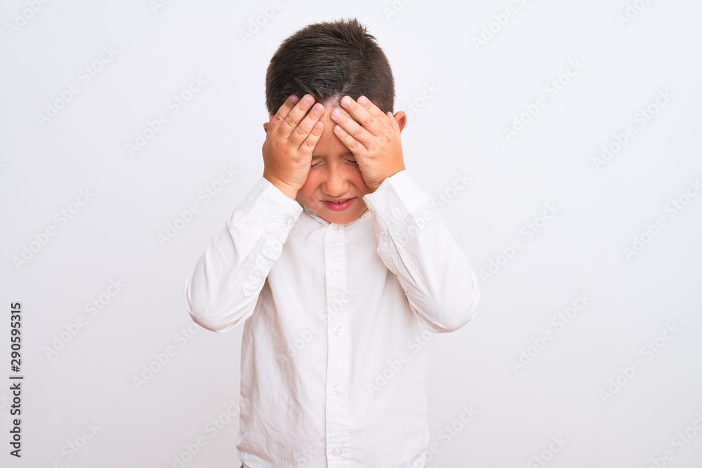 Beautiful kid boy wearing elegant shirt standing over isolated white background suffering from headache desperate and stressed because pain and migraine. Hands on head. Beautiful kid boy wearing elegant shirt standing over isolated white background suffering from headache desperate and stressed because pain and migraine. Hands on head.