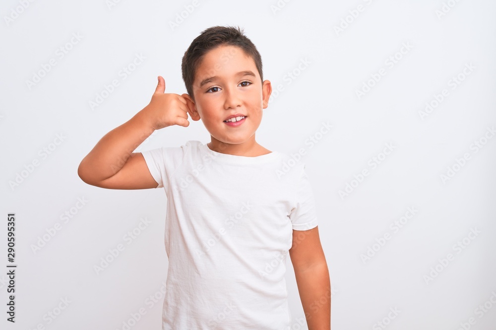 Beautiful kid boy wearing casual t-shirt standing over isolated white background smiling doing phone gesture with hand and fingers like talking on the telephone. Communicating concepts. Beautiful kid boy wearing casual t-shirt standing over isolated white background smiling doing phone gesture with hand and fingers like talking on the telephone. Communicating concepts.