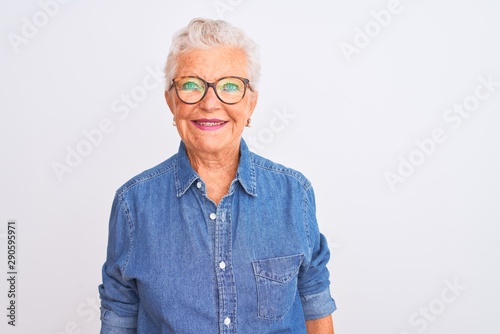 Senior grey-haired woman wearing denim shirt and glasses over isolated white background with a happy and cool smile on face. Lucky person.