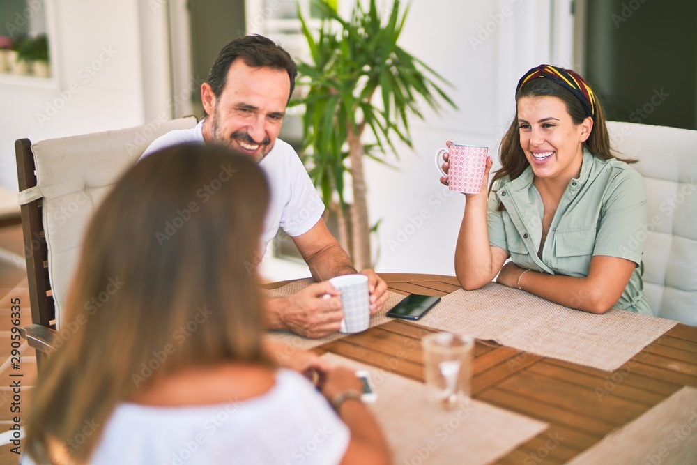 Beautiful family sitting on terrace drinking cup of coffee speaking and smiling Beautiful family sitting on terrace drinking cup of coffee speaking and smiling