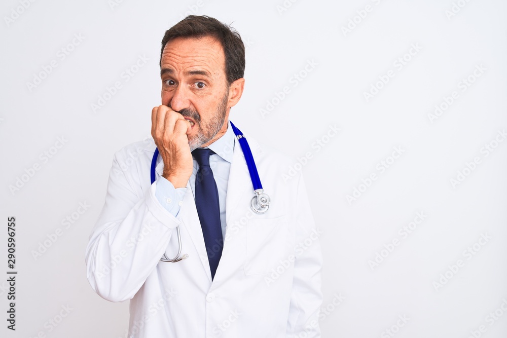 Middle age doctor man wearing coat and stethoscope standing over isolated white background looking stressed and nervous with hands on mouth biting nails. Anxiety problem. Middle age doctor man wearing coat and stethoscope standing over isolated white background looking stressed and nervous with hands on mouth biting nails. Anxiety problem.
