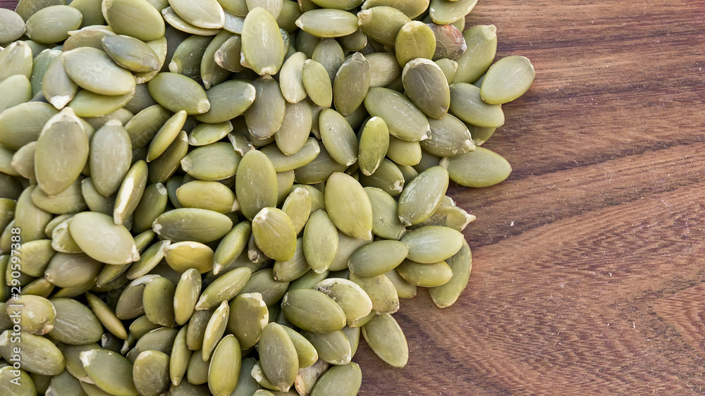 Green pumpkin seeds on wooden white background. Copy space Green pumpkin seeds on wooden white background. Copy space