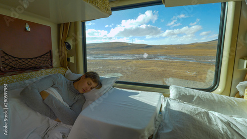 Tableau sur toile CLOSE UP: Tired girl sleeps in her sleeper cabin during train ride across Tibet