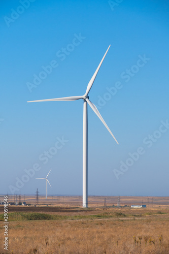 Huge wind generators against blue sky, close up. Spinning wind turbines on blue sky background, close up 
