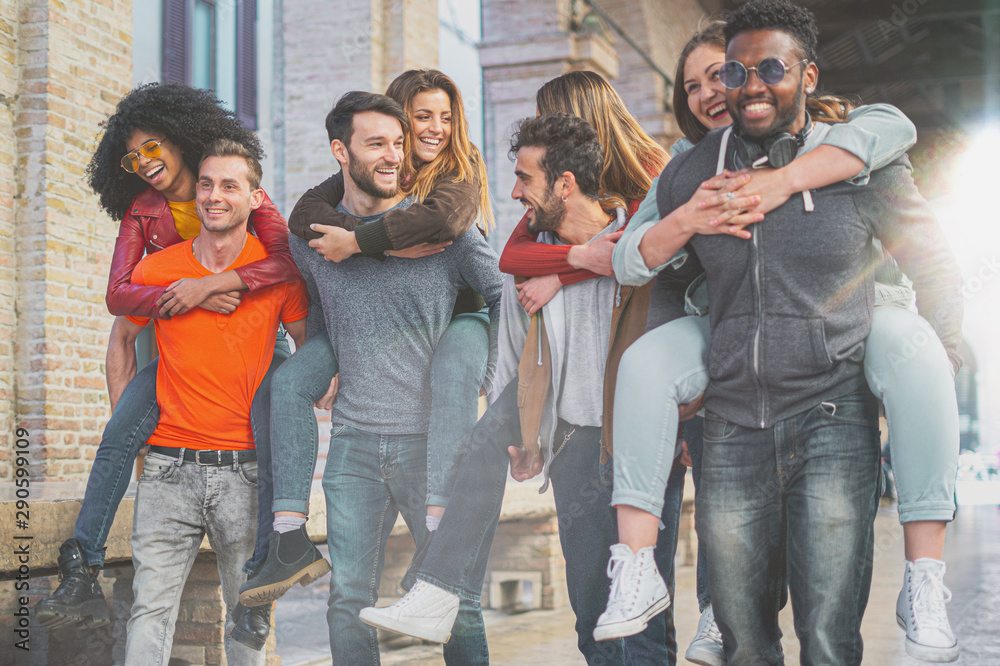 Fototapeta premium Four multiracial couples having fun piggybacking under the city arcades in the morning. Students having fun in the city..