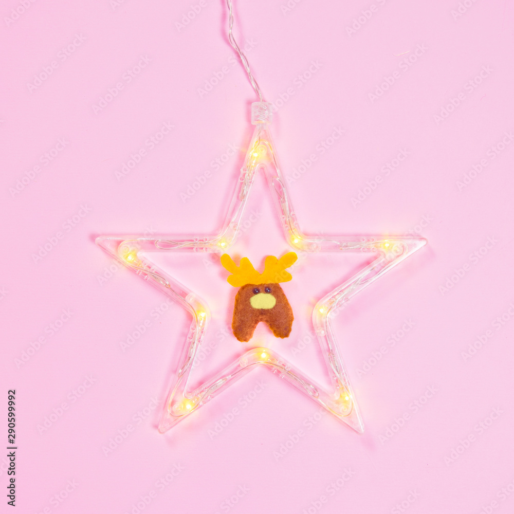 Glowing star with a deer on a pink background. Minimal flat lay Christmas theme. New year sale concept.