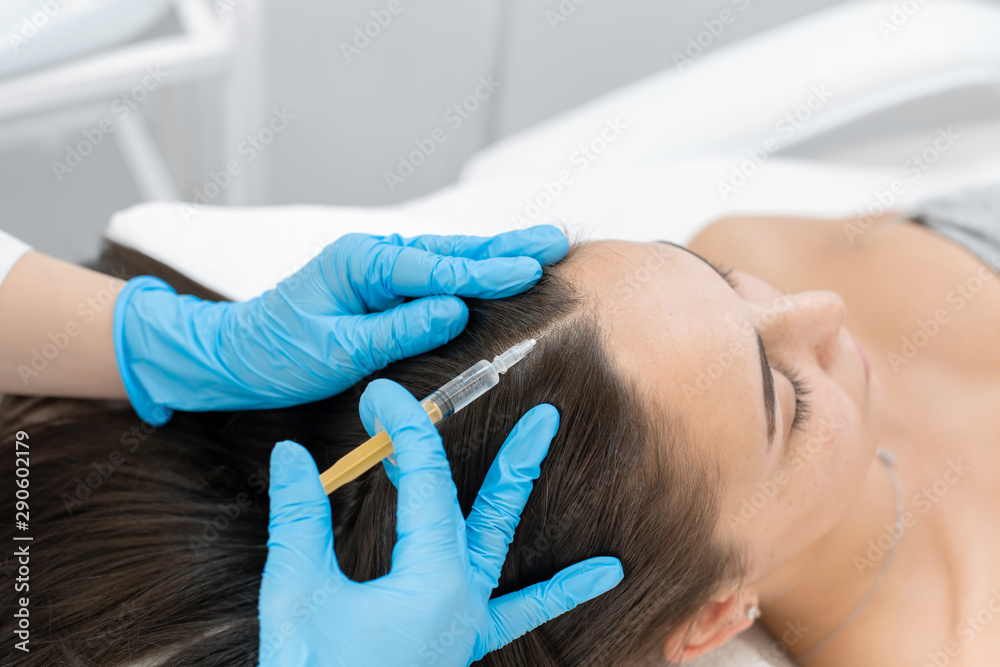 Beautician injections for healthy hair growth. Mesotherapy of the scalp. A young girl is undergoing a course of spa treatments in the office of a beautician. Moisturizing, cleaning and facial skin Beautician injections for healthy hair growth. Mesotherapy of the scalp. A young girl is undergoing a course of spa treatments in the office of a beautician. Moisturizing, cleaning and facial skin