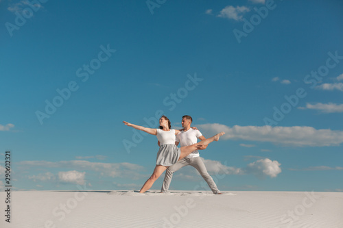 Romantic couple dancing in sand desert at blue sky background.