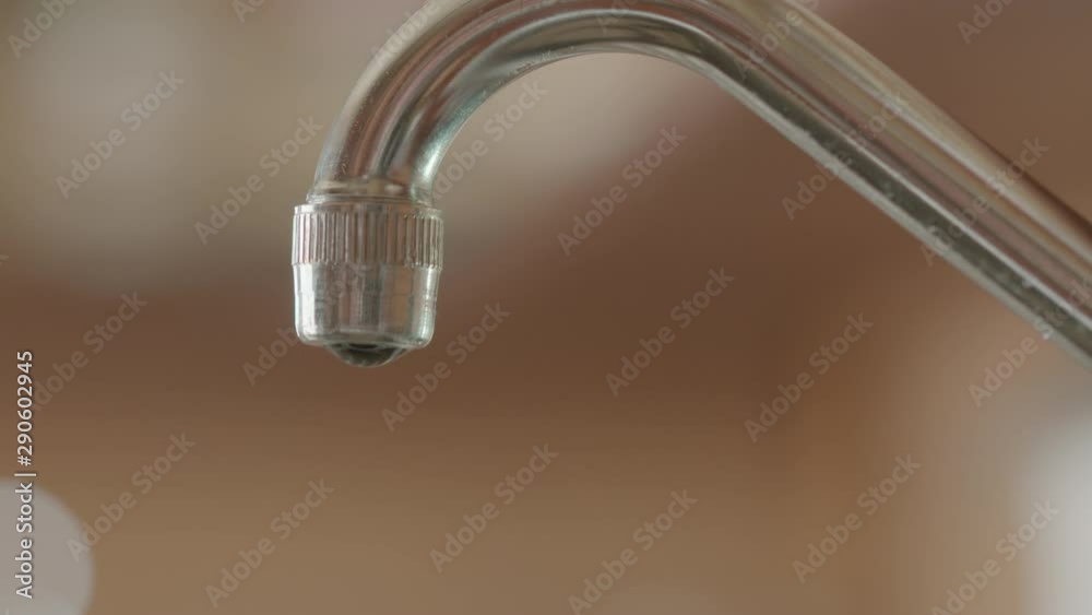 Shallow focus shot of water dripping out of a metal tap Shallow focus shot of water dripping out of a metal tap