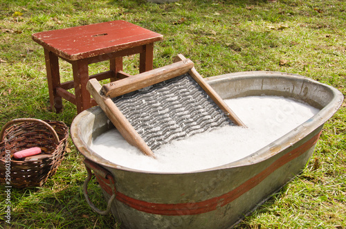 An old fashioned washing trougth filled with water, a vintage washboard and soap that wash the laundry photo
