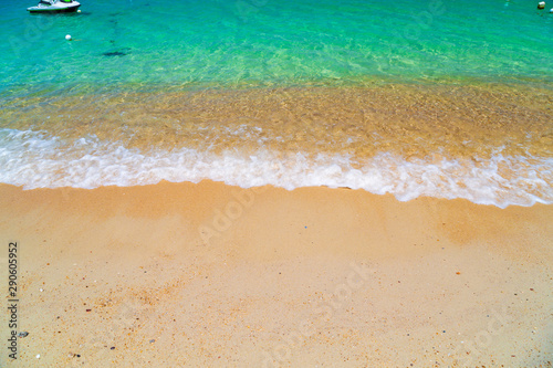 Ocean turquoise, yellow sand, waves, sunlight.