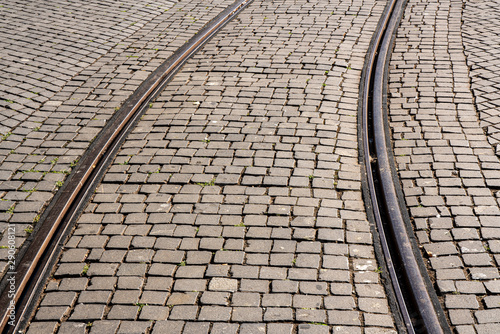 Curve of steel rails from tramcar track set into stone cobble pattern in Porto