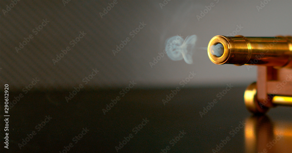 MACRO: A small cloud of smoke rolls out of the barrel of a miniature cannon. MACRO: A small cloud of smoke rolls out of the barrel of a miniature cannon.