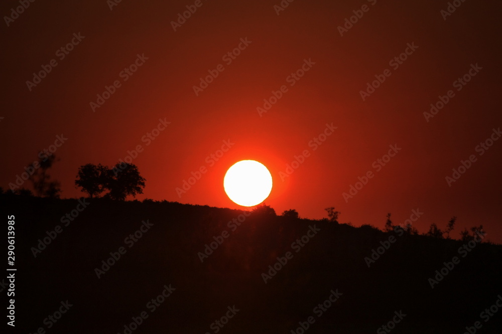 the sun sets after a hill