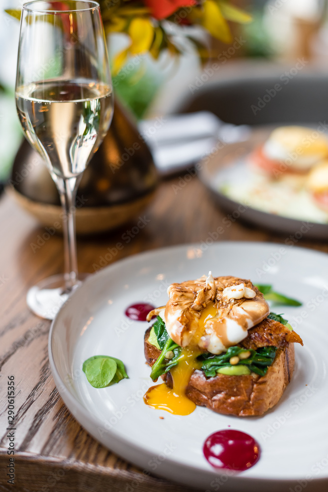 Served table for savory breakfast. Poached egg with smoked eel and sauteed spinach on brioche toast. Served table for savory breakfast. Poached egg with smoked eel and sauteed spinach on brioche toast.