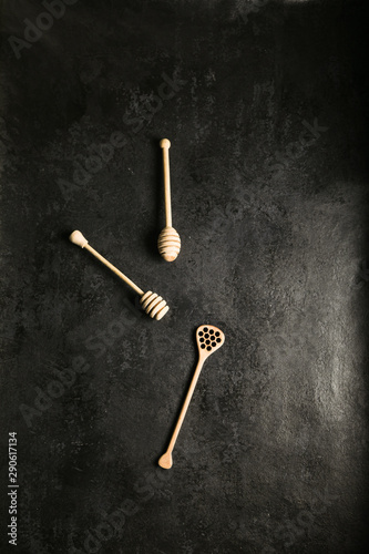 Wooden honey stick on concrete or stone dark background. Copyspace.