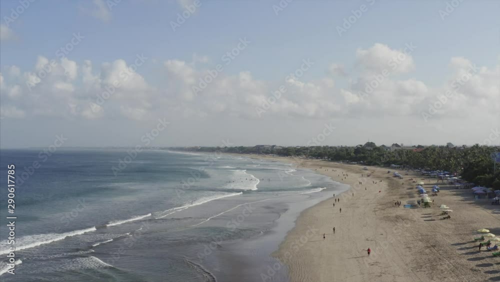 Aerial view of nice sandy Kuta beach and blue ocean in the morning. Tourists are walking along the beach. Bali, Indonesia Aerial view of nice sandy Kuta beach and blue ocean in the morning. Tourists are walking along the beach. Bali, Indonesia