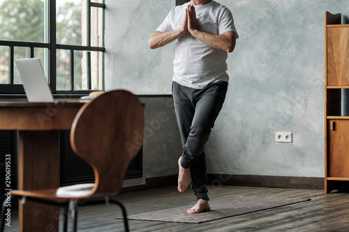 Man standing in one leg yoga balance variation. No face view. Healthy lifestyle at old age photo