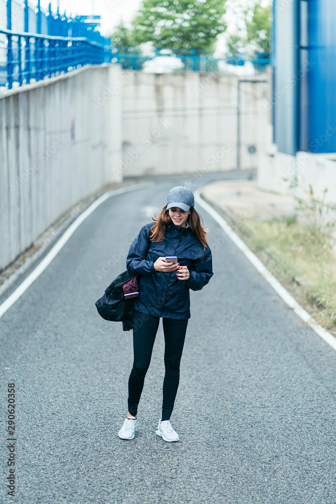 a young woman walking along the road with an smartphone with sport wear a young woman walking along the road with an smartphone with sport wear