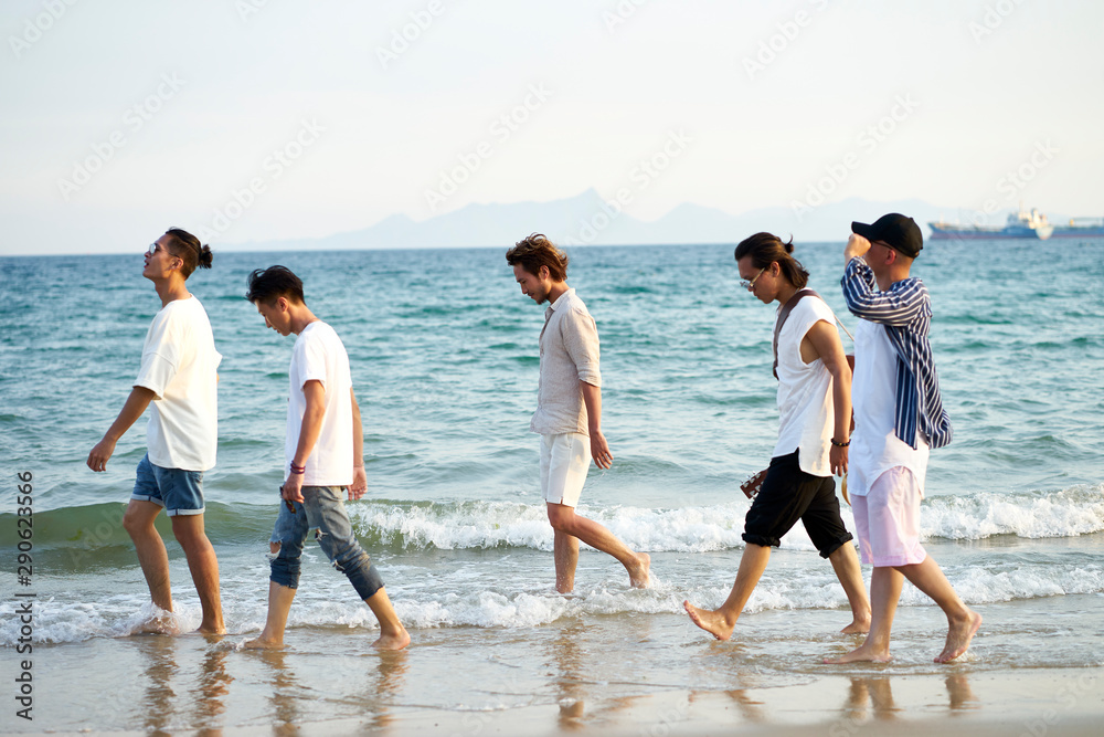 group of asian men walking on beach