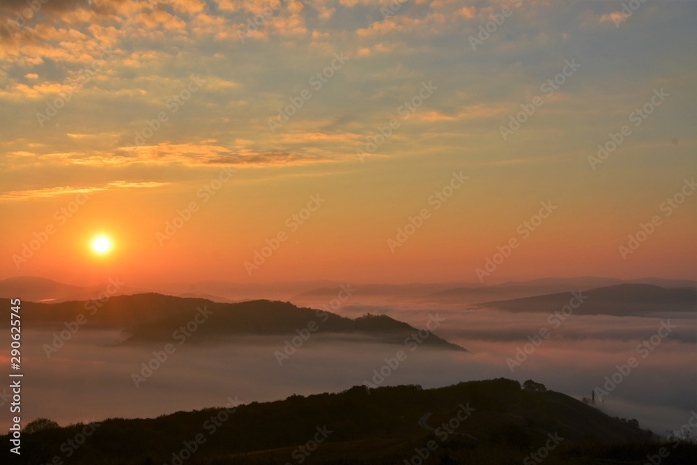 sunset over mountains with fog in the valleys