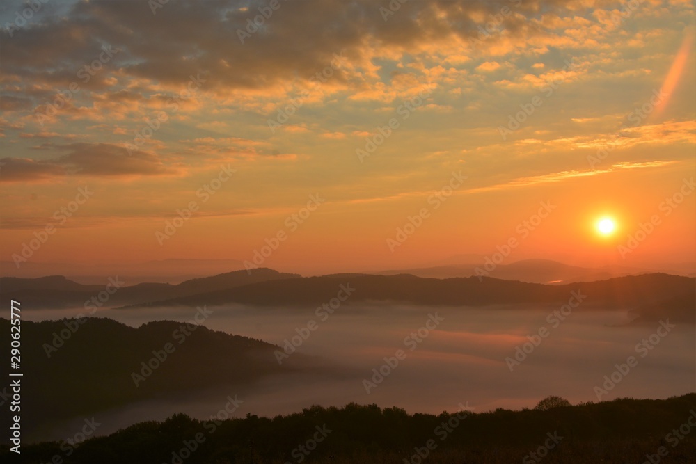 sunset over mountains with fog in the valleys