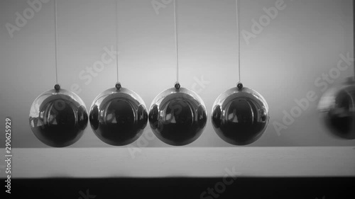 Newton's cradle in motion, five-ball system in one-ball swing. Black and white, slow motion, close up shot with white background. photo