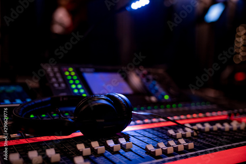 Headphones lying on an advances mixing console in dim lighting in an event venue