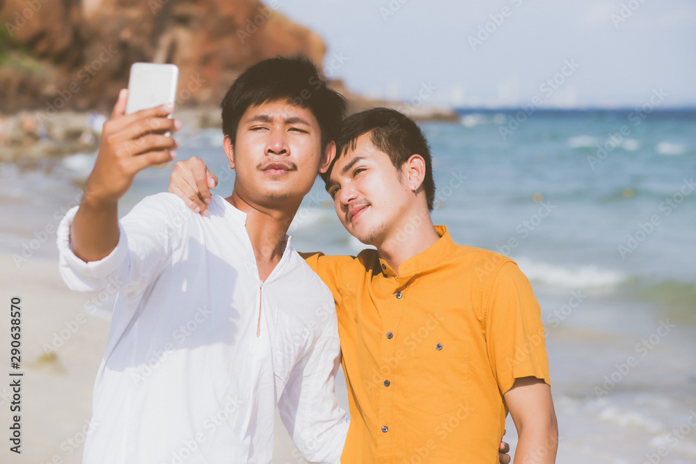 Gay portrait young couple smiling taking a selfie photo together with smart mobile phone at beach, LGBT homosexual lover in the vacation at sea, two man going to travel, holiday concept. Gay portrait young couple smiling taking a selfie photo together with smart mobile phone at beach, LGBT homosexual lover in the vacation at sea, two man going to travel, holiday concept.