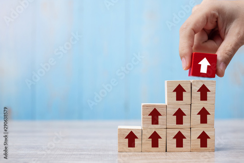 Businessman hand placing or pulling Red block with arrow and growth up arrow on table background. Business Growth, Improvement, strategy, Successful, success, winner and Mission complete Concepts