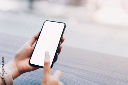 Closeup of woman holding a smartphone, mock up of blank screen. using cell phone on cafe. Technology for communication concept.