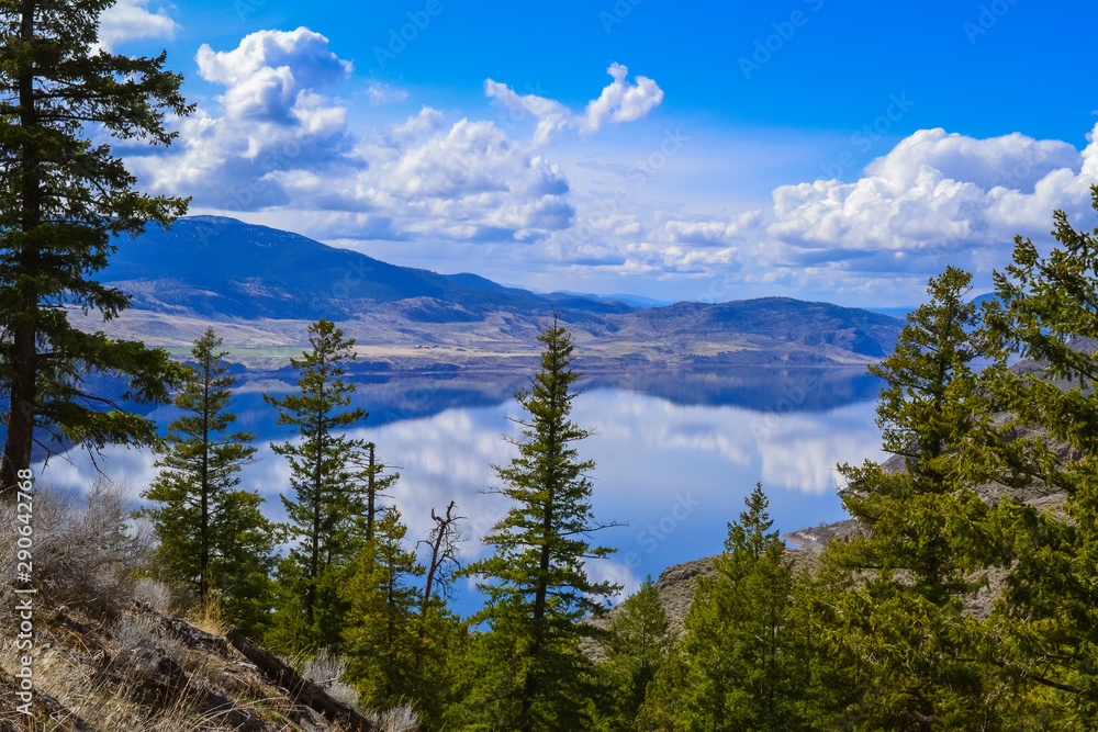 View of kamloops lake from Battle Bluff hike, clouds and mountains are reflecting in the calm lake, rocks
