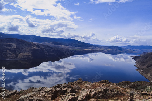 View of kamloops lake from Battle Bluff hike  clouds and mountains are reflecting in the calm lake  rocks