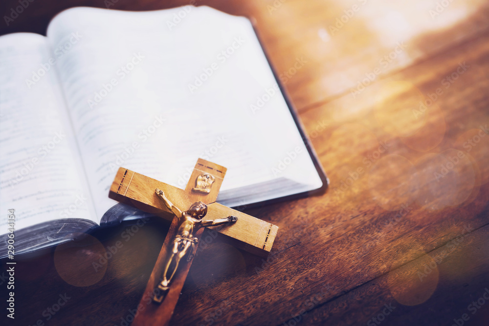 Obraz premium Close up of Jesus's crucifix over bible on wooden table background, copy space