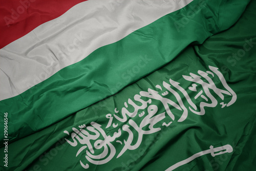 waving colorful flag of saudi arabia and national flag of hungary.