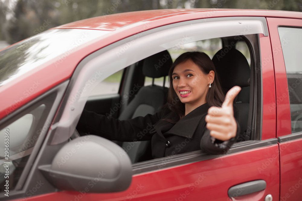 Happy woman inside a car driving in the street and gesturing thumb up