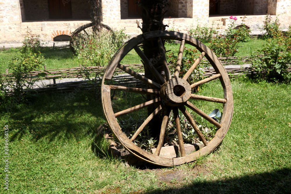 An old wooden wagon wheel on green grass