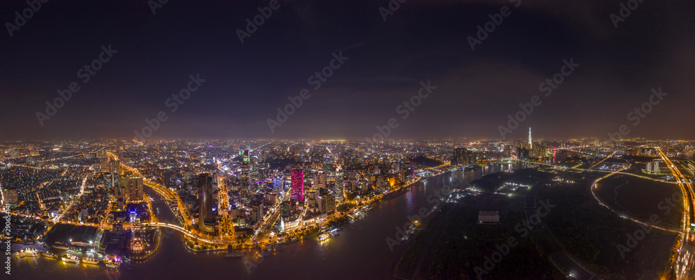 Ultra high resolution aerial panorama of Ho Chi Minh City or Saigon Vietnam under lights at night featuring all Landmark Buildings and Saigon River